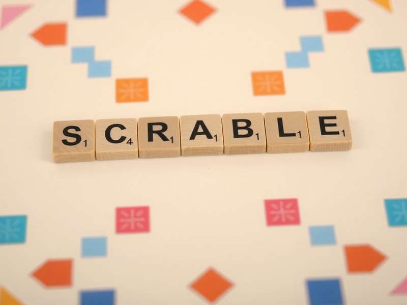 A close-up of colorful Scrabble tiles arranged to spell 'WORD' on a wooden board in India